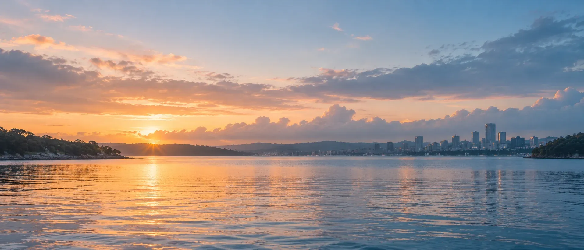Calm harbour water at first light with distant shoreline and low cloud, no people in frame